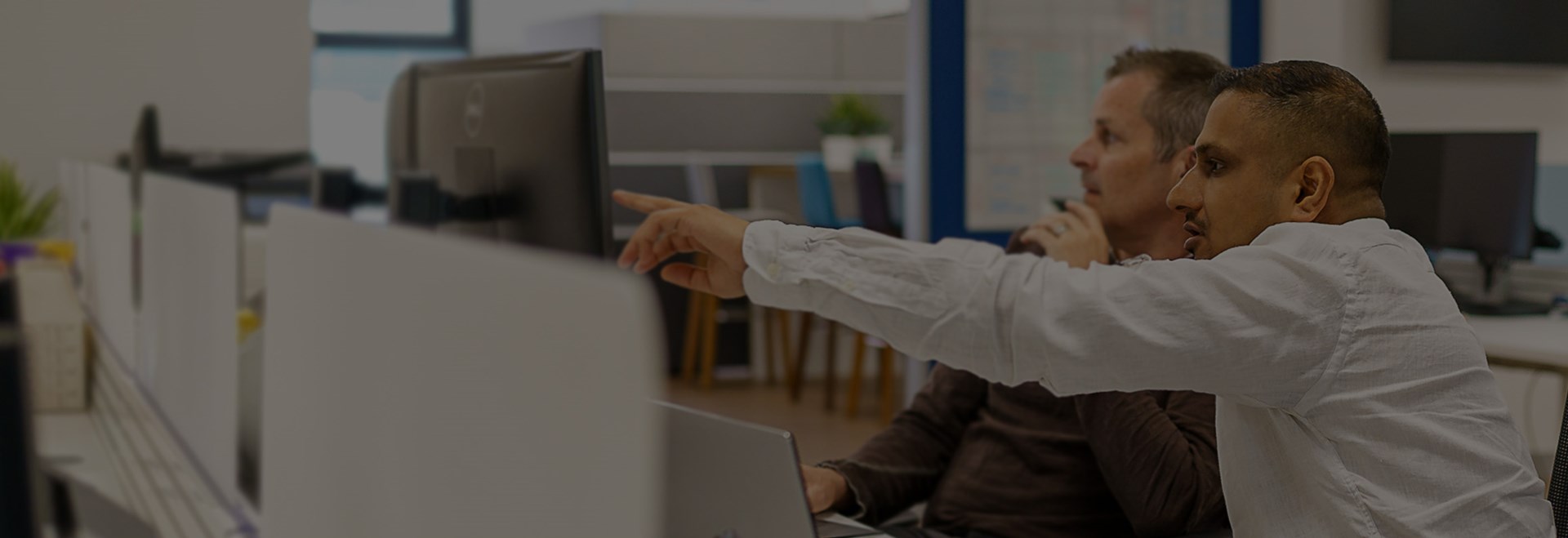 Two men pointing at computer working