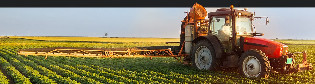 Farming tractor in field spraying crops