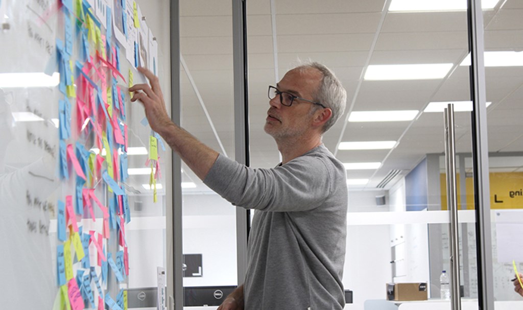 Man pointing at board with postIt notes on